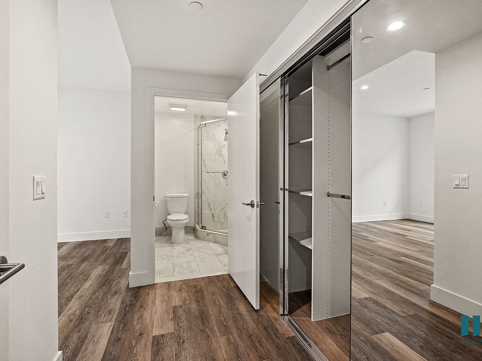Bedroom with Large-Size Mirrored Closet with Built-In Shelving and Bathroom