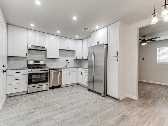 Kitchen featuring stainless steel appliances, white cabinetry, tasteful backsplash, light wood-style flooring, and recessed lighting