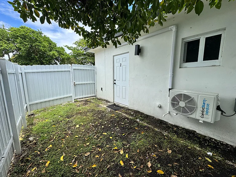 Fenced side yard entry with a private exterior door, security lighting, and easy access to the home's HVAC area.