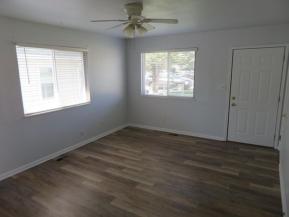 Living room with new luxury vinyl plank floor, ceiling fan and new plantation blinds. front coat closet in corner.