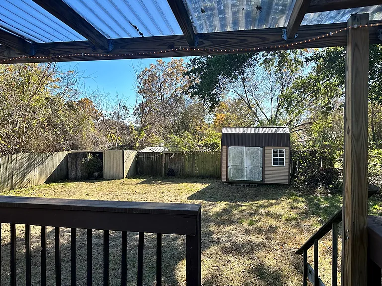 Fenced backyard w/ covered patio and storage