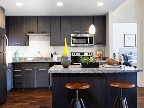 Open kitchen with stainless steel appliances and breakfast bar.