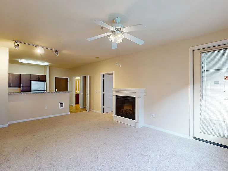 Apartment kitchen, dining and living room with plush carpet flooring.