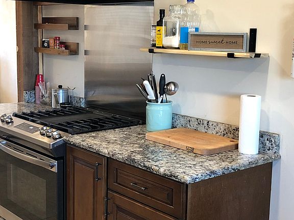 Gas range oven with exhausted vent hood & granite countertops.