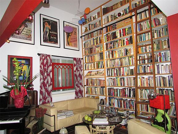 The library or reading room features this wonderful floor to ceiling built in bookshelf with antique rolling ladder. Formerly th