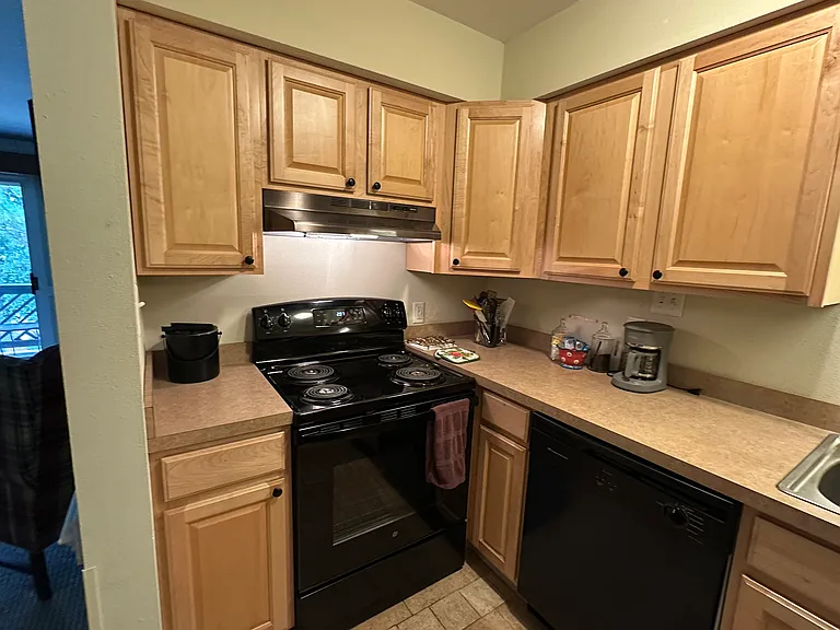 Kitchen with electric range, coffee maker, fully furnished utensils, dishes, and pots and pans.