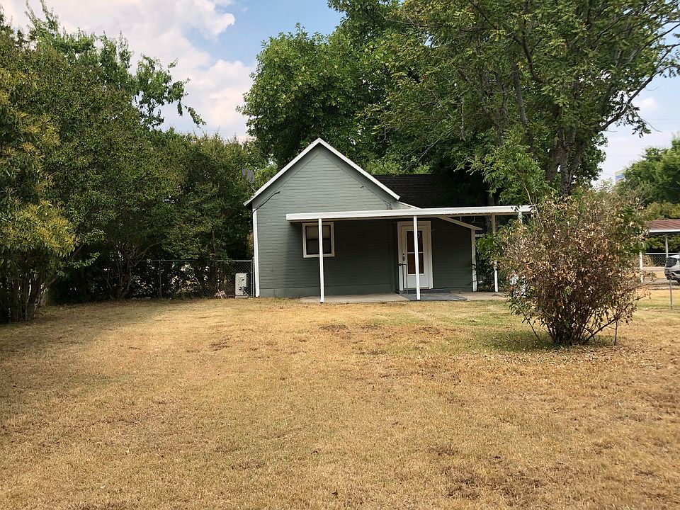 Front of house with fenced in yard and covered car port