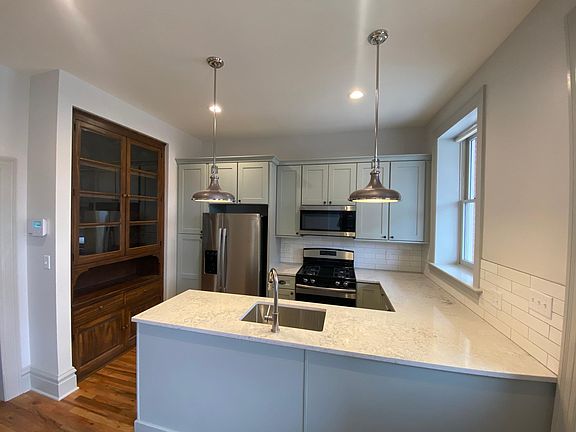 Stunning kitchen with large quartz countertop, custom-built stained butler pantry, stainless steel appliances.