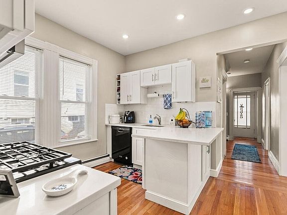 kitchen with quartz countertop, stainless steel appliances, hardwood floors, washing machine, dryer, and dishwasher