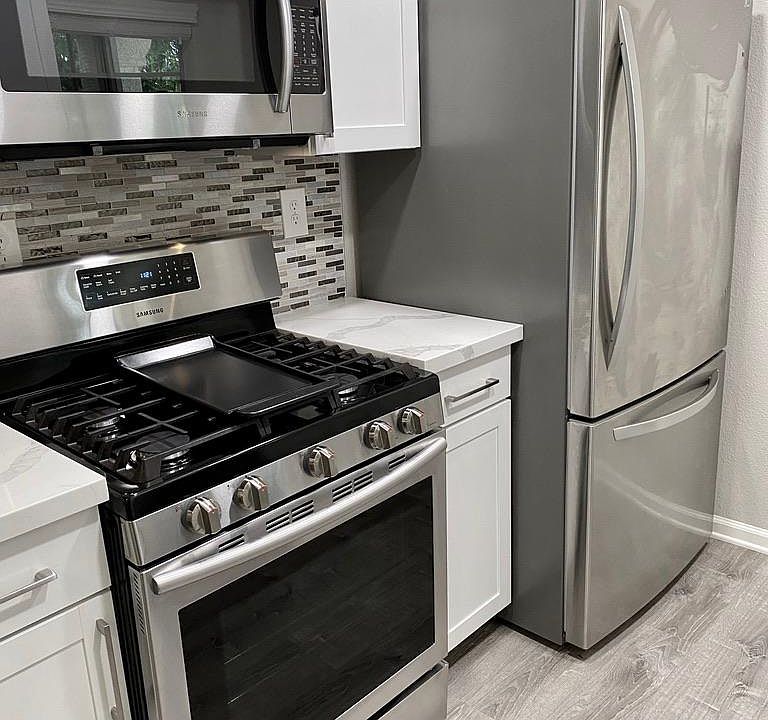 Full sized STAINLESS STEEL gas oven, cook-top and bottom freezer refrigerator.