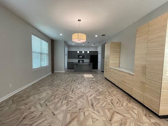Kitchen with decorative light fixtures, a center island with sink, open floor plan, recessed lighting, and black microwave