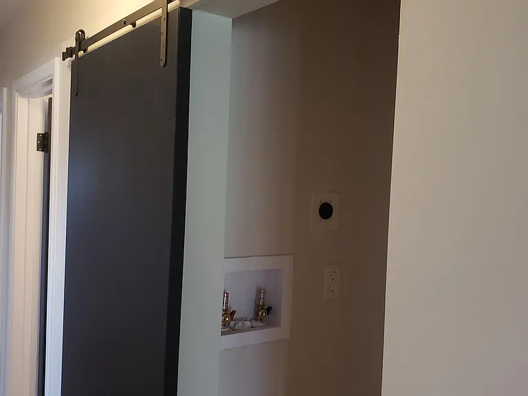 Stack washer and dryer behind barn door.