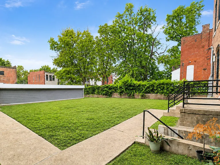 Expansive rear lawn provides valuable outdoor space with paved walkways and convenient access to the building and garage.