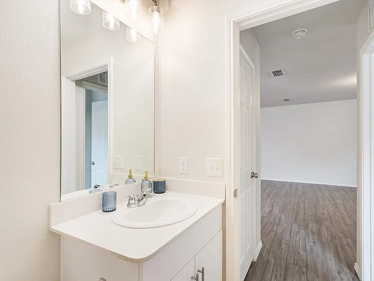 Vanity featuring a white countertop with an integrated sink, polished chrome faucet, and a large wall-mounted mirror