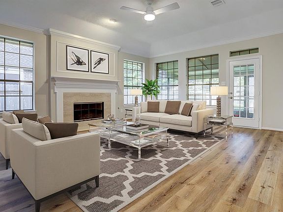 Living room has stylish floors, oversized fireplace, ceiling fan, access to the screened in back porch, and windows galore! Virtually staged.