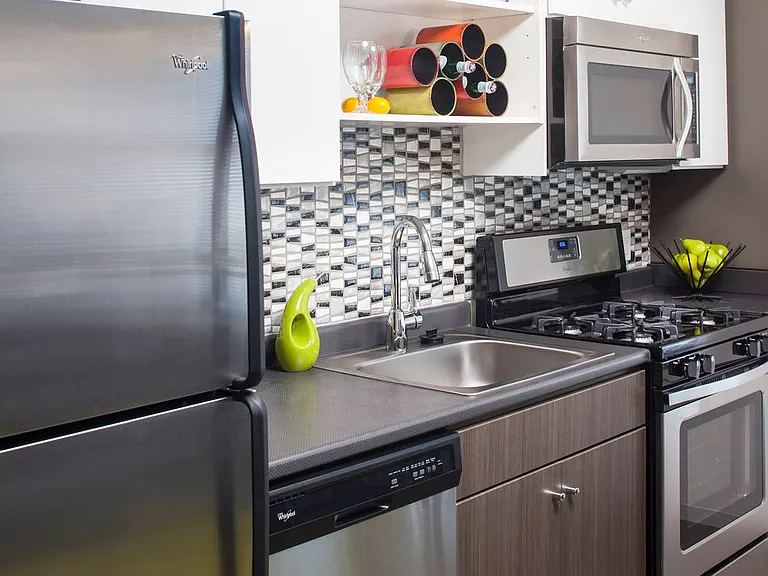 Classic Package II kitchen with stainless steel appliances, dark laminate countertops, white and brown cabinetry, tile backsplash, and hard surface flooring