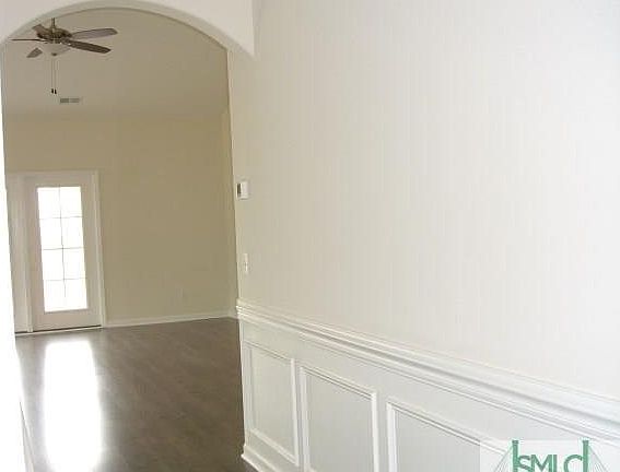 VIEW FROM FOYER INTO GREAT ROOM WITH LAMINATE FLOORINGL, ARCHED ENTRY WAY AND WAINSCOTING
