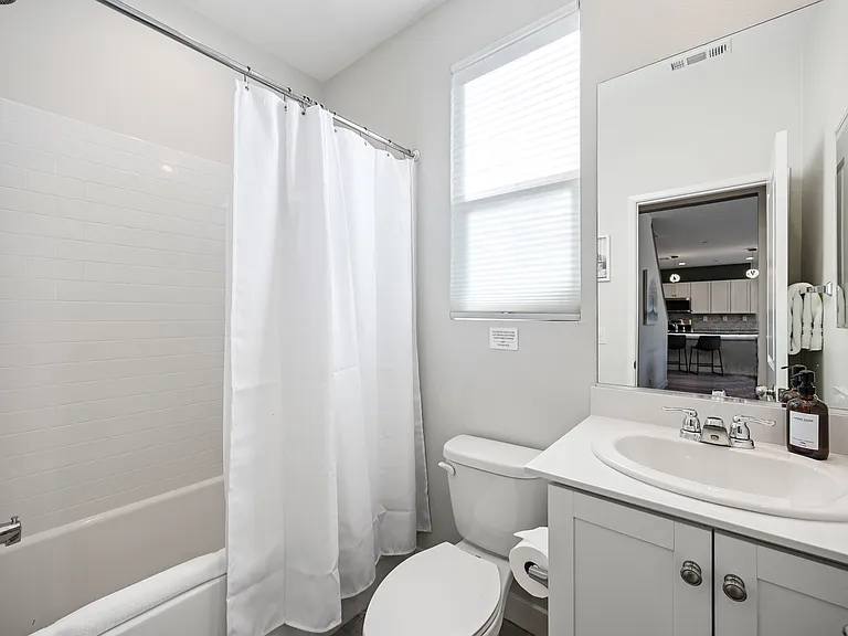 Full Bathroom 4 is located in the lower level right next to Bedroom 6 and features a bathtub shower combo with decorative vanity sink and toilet.