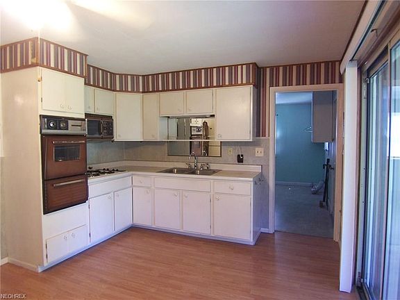 The kitchen has white cabinets and a vintage wall oven.