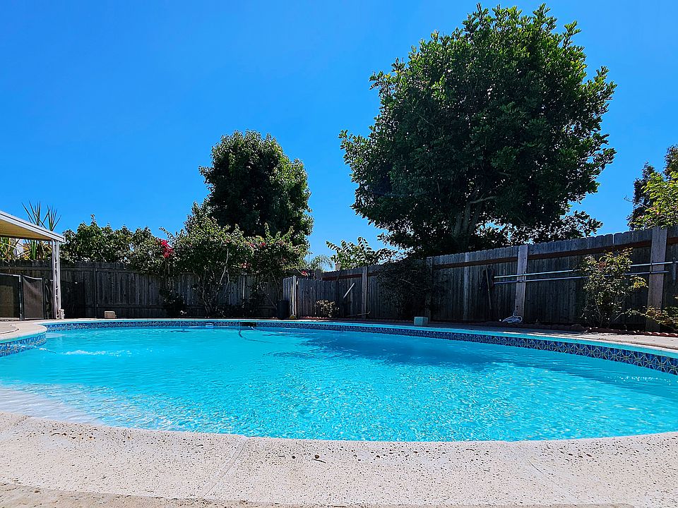 Fenced-in back yard with a sparking pool