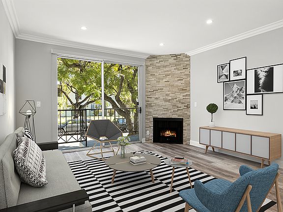 Hardwood floored living room with balcony access and stone walled fireplace.