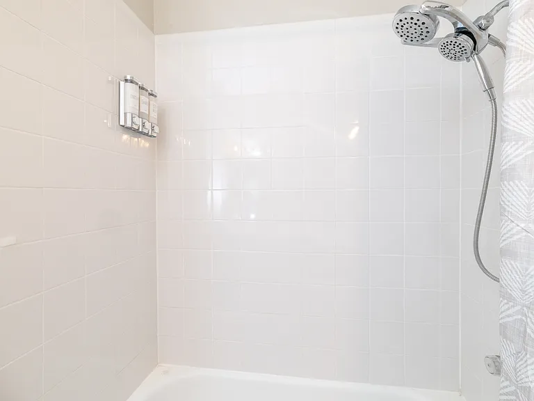 Bathroom 1 features a tub/shower combo and his-and-hers sinks on an L-shaped counter. Stocked with soap, shampoo, and conditioner for your convenience. Located on the first floor.
