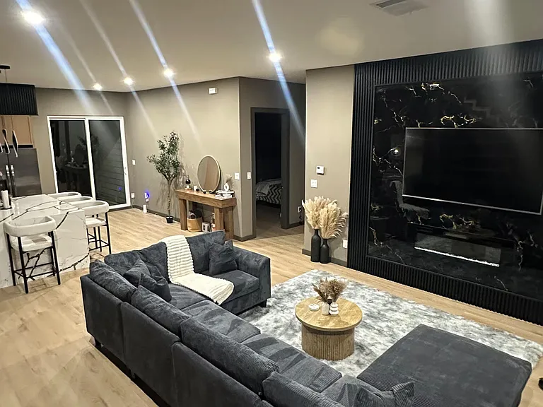 Open-concept living area with sectional seating, large TV feature wall, and easy flow to the kitchen island bar.