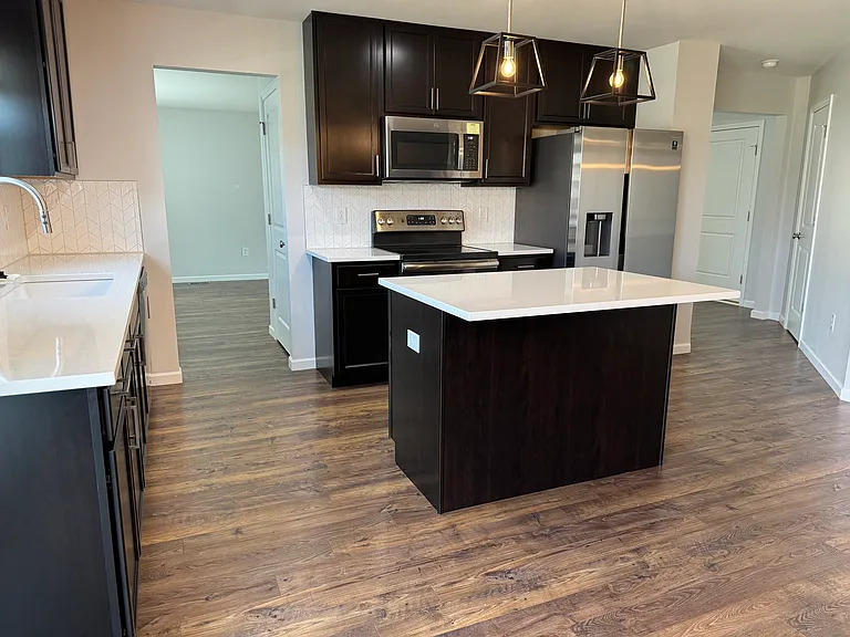 White quartz countertops and stainless steel appliances grace this modern kitchen with touch free faucet and upgraded fixtures