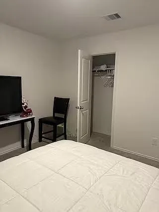 Private bedroom with a furnished sleeping area, TV setup, and an open closet with shelving and hanging space.