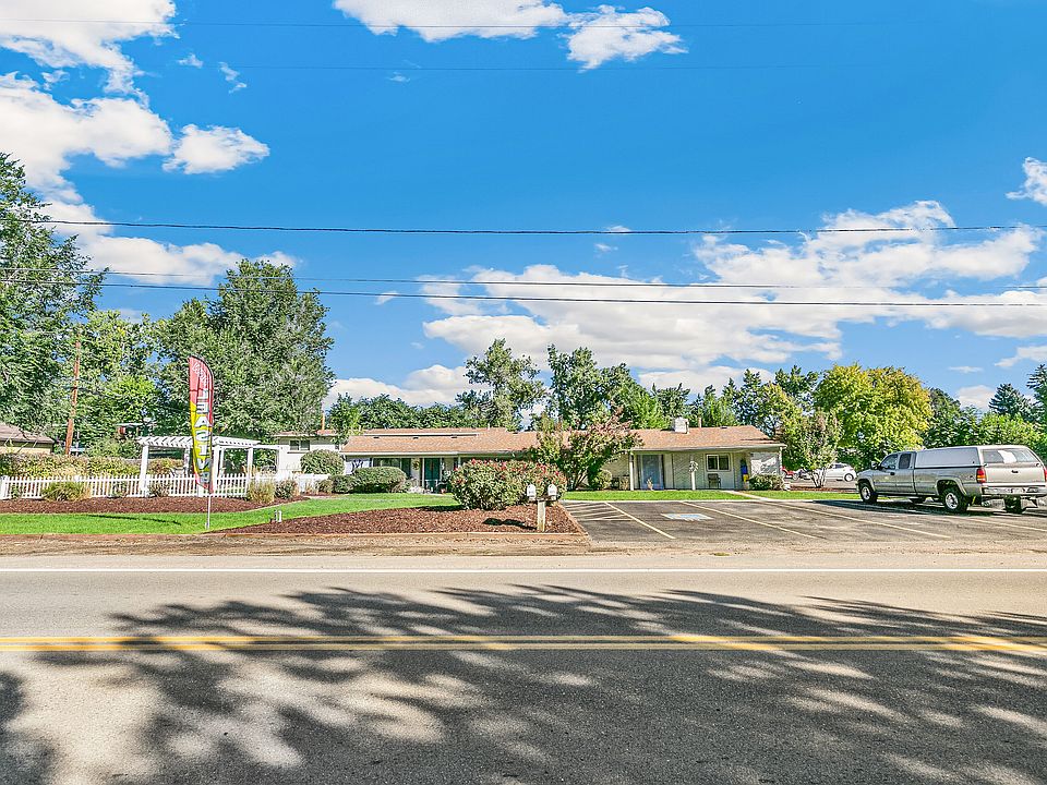Charming entry sign for The Elms Apartments surrounded by lush greenery and vibrant flowers, located at 1025-1055 Ammons St, offering a welcoming and scenic environment.