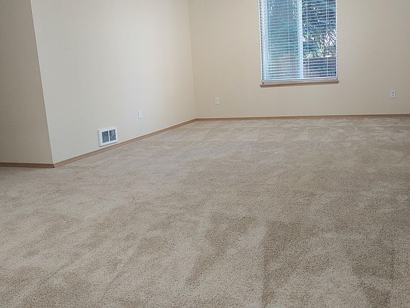 Another view of the living room which wraps around into The hallway leading to the two bedrooms and the bathroom.