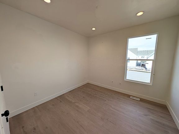 Cozy room with wooden floor, white walls, recessed lights, and window views of neighboring Voyager