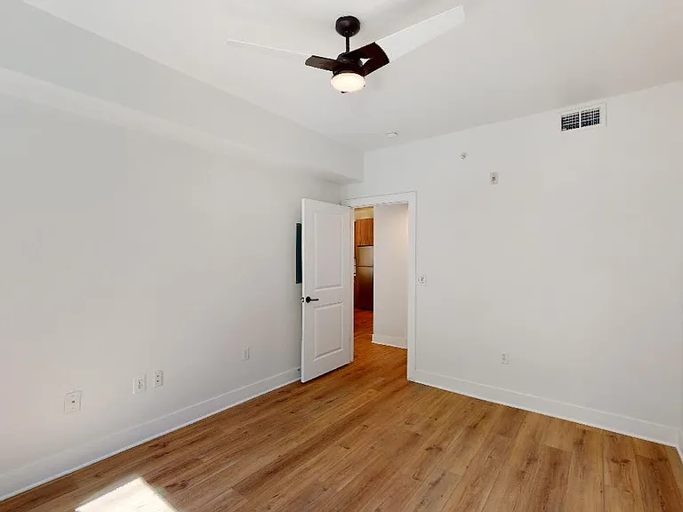 Spacious apartment bedroom with wood-style flooring.