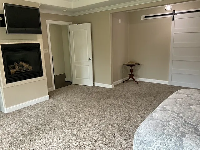 Enter Primary Bedroom with gas fireplace, balcony and view of pond in back.