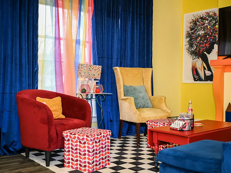 Colorful living area with lounge seating, window coverings, and a TV setupideal for relaxing or socializing.