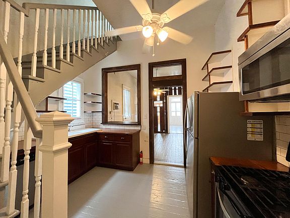 Spacious kitchen area withs stairs leading to primary bedroom with walk-in closets.