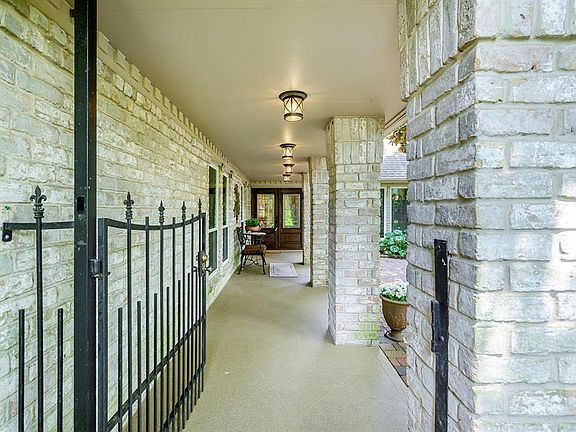 Wrought iron entry gate opens to a long lighted pathway leading to beveled glass front doors.