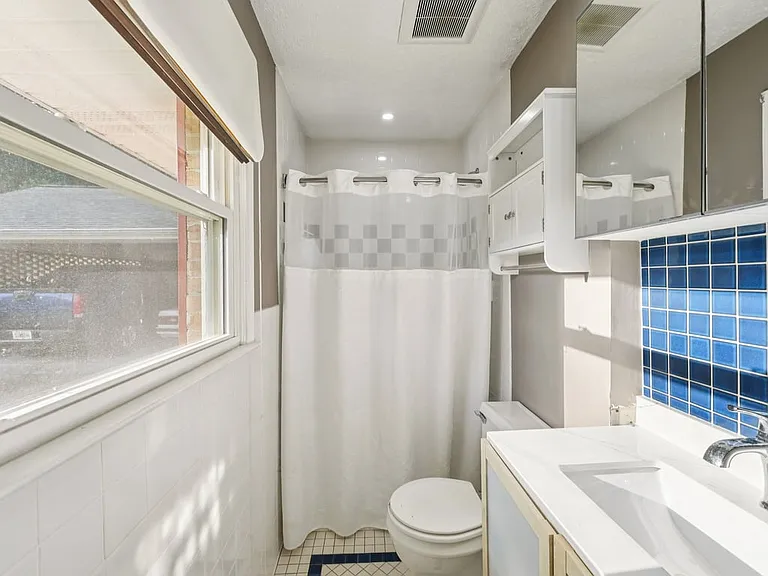 A bright and cheerful bathroom where crisp white finishes, classic tile, and a playful blue accent create a fresh little retreat with charming personality.