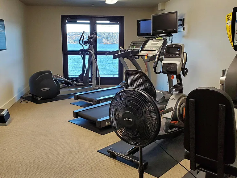 Fitness room with balcony and water view