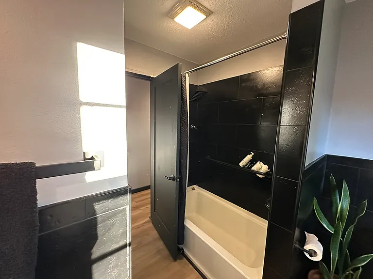 Main floor bathroom includes bathtub, rainfall showerhead and half wrap tile around entire space.