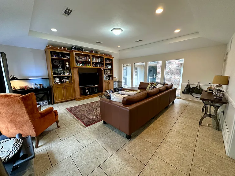Family room area featuring light tile patterned flooring, and a raised ceiling.
