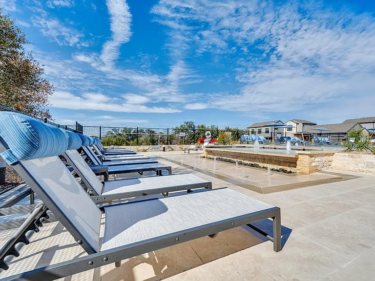 A row of sun loungers are in the foreground of a sunny day.