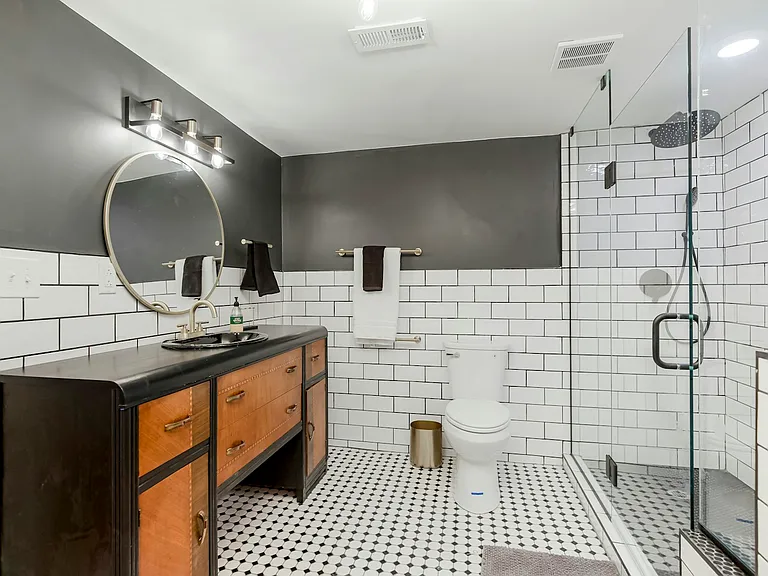 The bathroom's art deco themed vanity and spacious shower