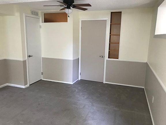 Lower level living room. Grey door to washer/dryer area, white door to furnace/water heater. More storage under stairs. South window on the right.