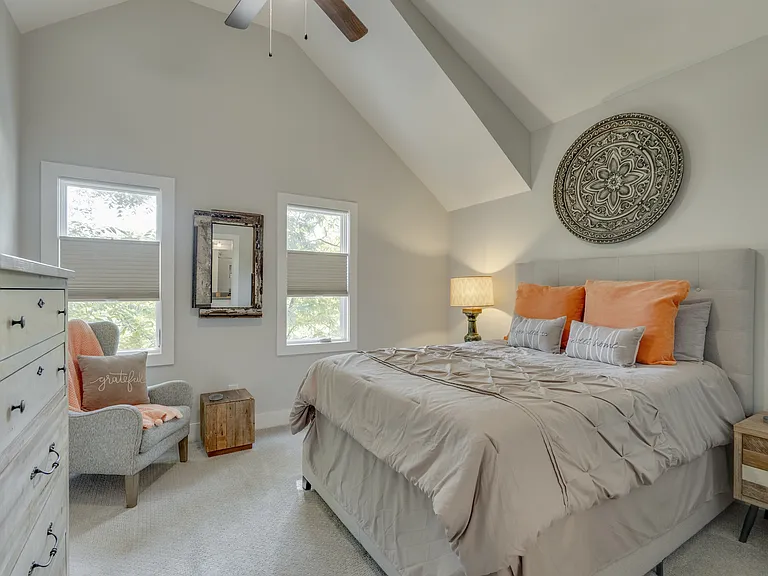Beautifully appointed second ensuite bedroom featuring a plush pillow-top queen bed, large windows with top-down/bottom-up blackout shades, a walk-in closet, spacious dresser, comfortable seating, USB charging ports, and a private ensuite bathroom.