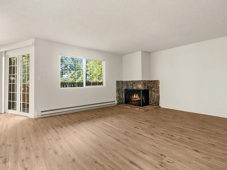 Bright and inviting! This open-concept living room features stunning wood-style floors, a charming stone fireplace, and plenty of natural light. Bright and inviting! This open-concept living room features stunning wood-style floors, a charming stone firep