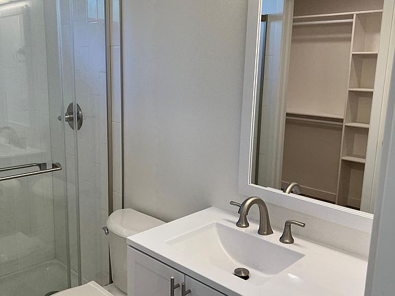 Primary bathroom with walk in closet visible in the mirror