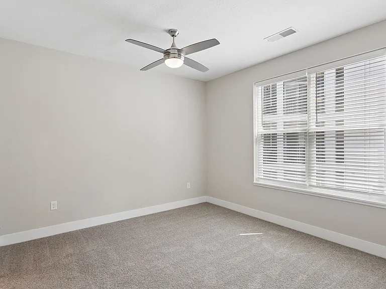 Carpeted bedroom with ceiling fan of a Tiffany Flats apartment home.