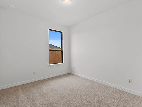 Third bedroom with abundant windows, carpeted floors, and a spacious closet, filled with natural lig