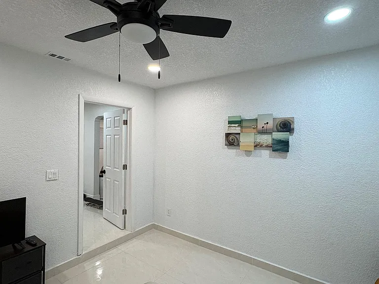 Tiled bedroom with a ceiling fan, recessed lighting, and easy access to the adjacent bath/hallway for added convenience.